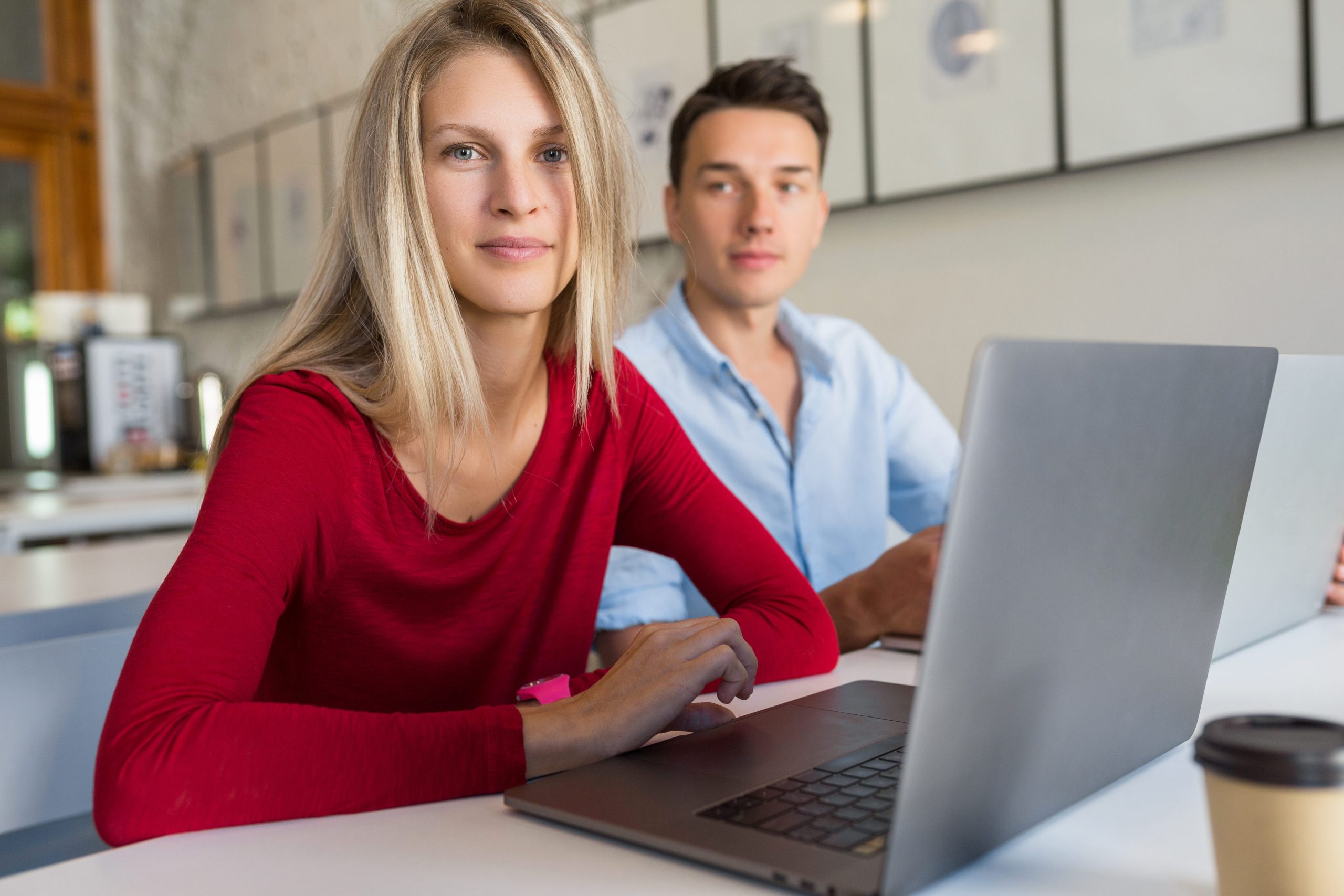 young man and woman working on laptop in open space co-working office room, freelancers, startup, creative job, education online, looking in camera