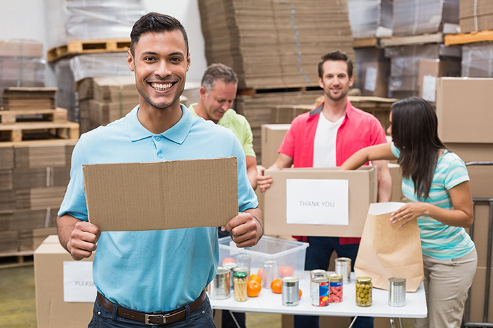 Smiling volunteer showing a poster in a large warehouse